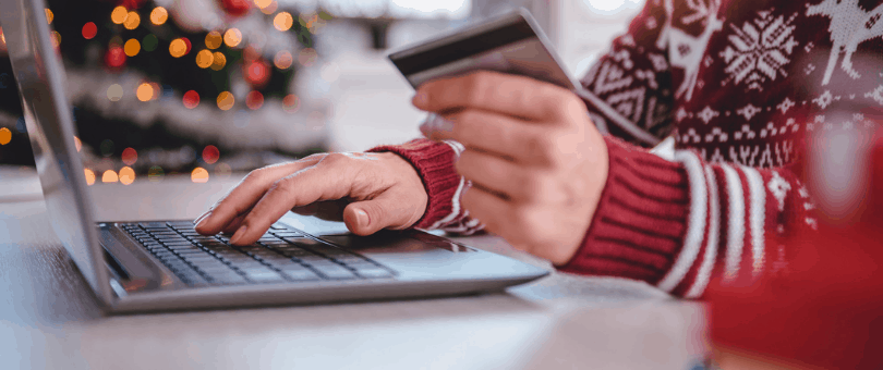 a hand with a credit card and laptop, online holiday shopping